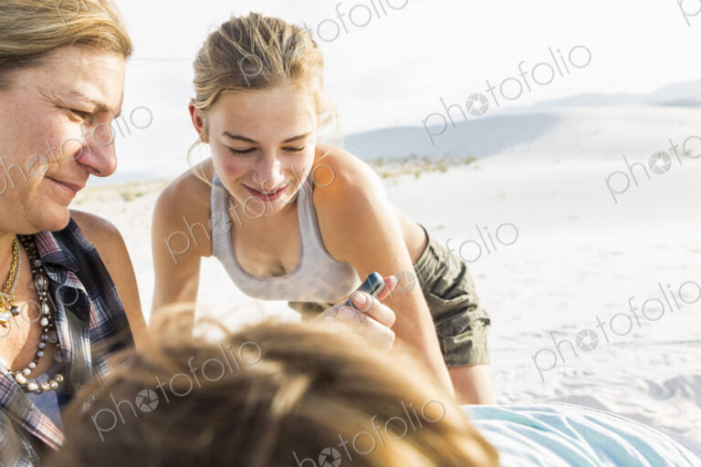 Mother looking at her smart phone as her kids look on