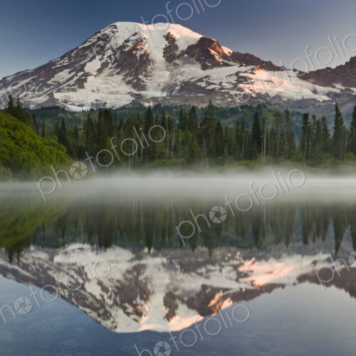 Mount Rainier, a snow capped peak, surrounded by forest reflected in one of many lakes… Mount Rainier, a snow capped peak, surrounded by forest reflected in one of many lakes…