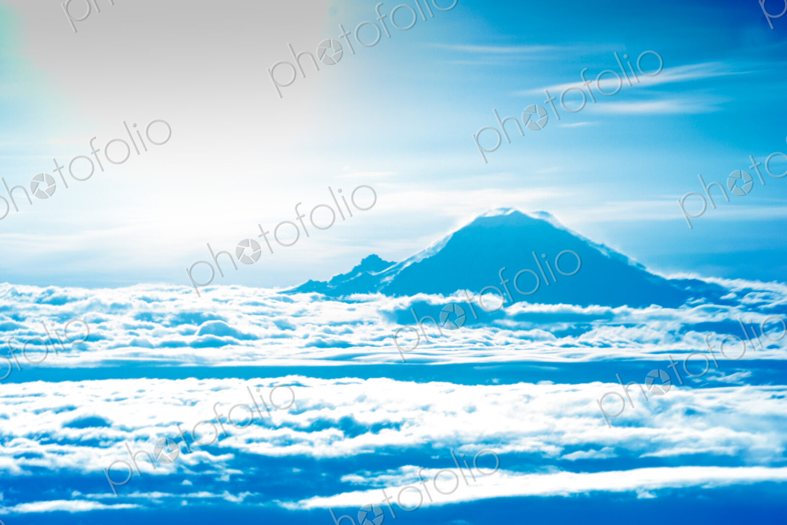 Mount Rainier summit appearing about the clouds, a view from a jetliner window.