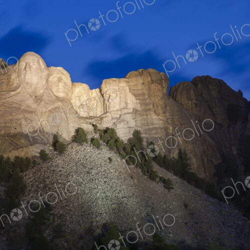 Mount Rushmore illuminated at dusk beneath a deep blue sky with soft cloud motion,… Mount Rushmore illuminated at dusk beneath a deep blue sky with soft cloud motion,…