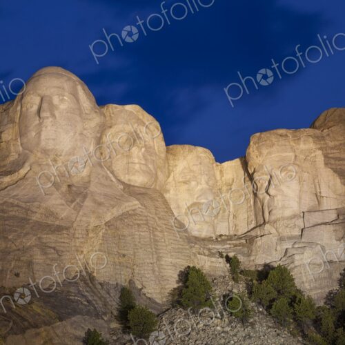 Mount Rushmore illuminated at dusk beneath a deep blue sky with soft cloud motion,… Mount Rushmore illuminated at dusk beneath a deep blue sky with soft cloud motion,…