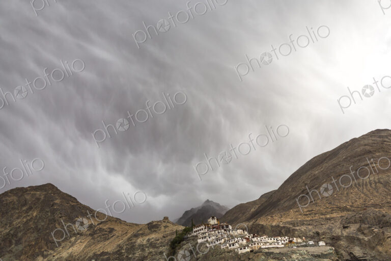 Mountain landscape with monastery under a cloudy sky.