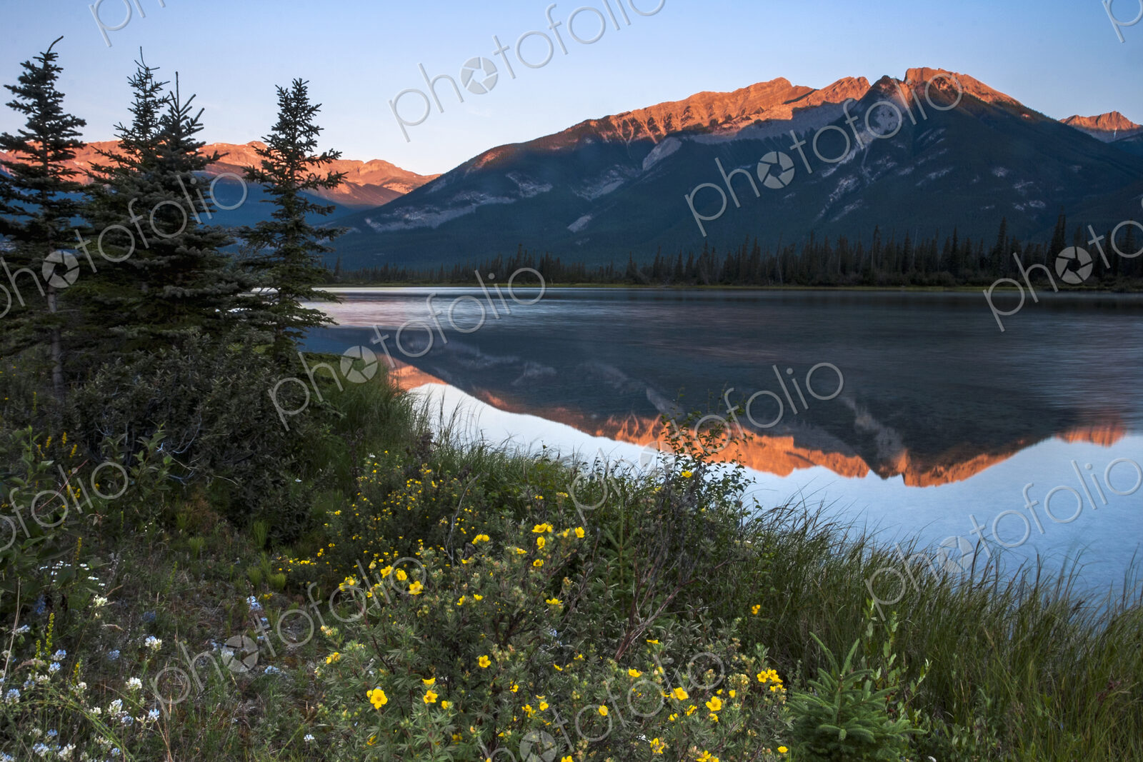 Mountains reflected in a lake and the sun reflecting off the snow covered high slopes.