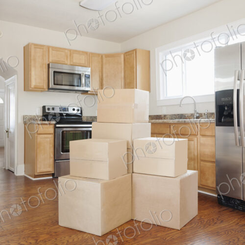 Moving house, relocation, cardboard boxes piled up in a house fitted kitchen