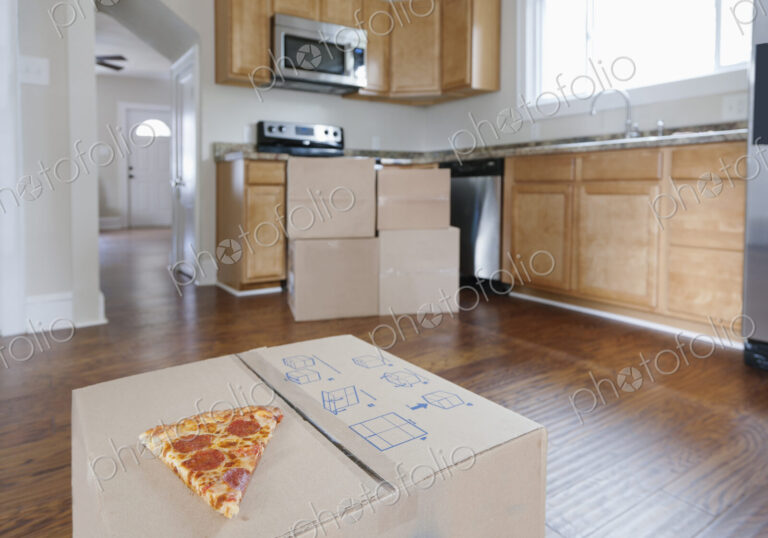 Moving house, relocation, cardboard boxes piled up in a house fitted kitchen, a slice…