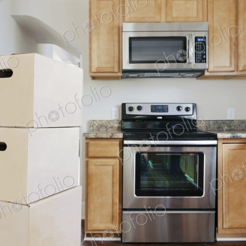 Moving house, relocation, cardboard boxes piled up in a kitchen.