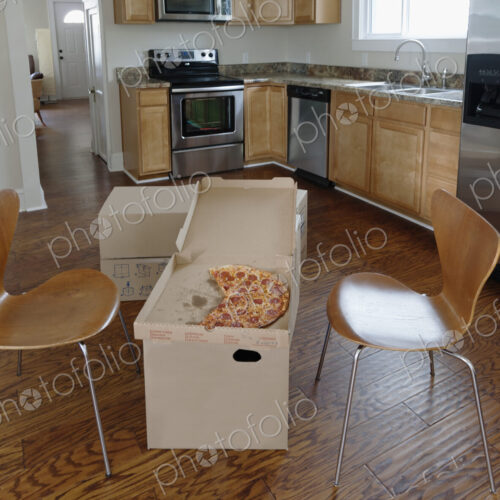 Moving house, relocation, cardboard boxes piled up in a kitchen, a pizza in a carton
