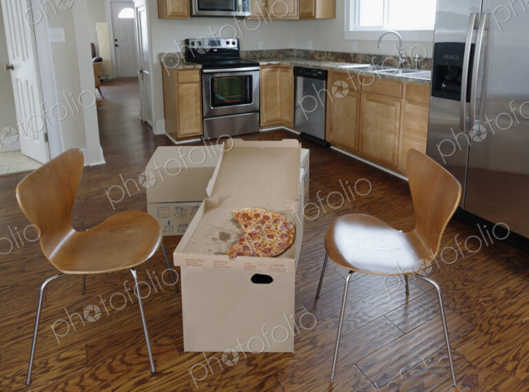 Moving house, relocation, cardboard boxes piled up in a kitchen, a pizza in a carton