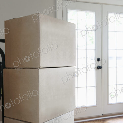 Moving house, relocation, cardboard boxes piled up in an empty house.