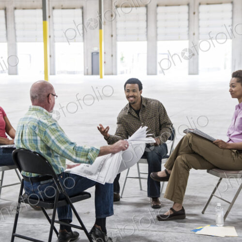 Multi-racial team of people going over plans for a new warehouse interior.