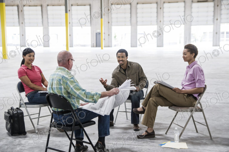 Multi-racial team of people going over plans for a new warehouse interior.
