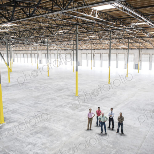 Multi-racial team of people going over plans for a new warehouse interior. Multi-racial team of people going over plans for a new warehouse interior.
