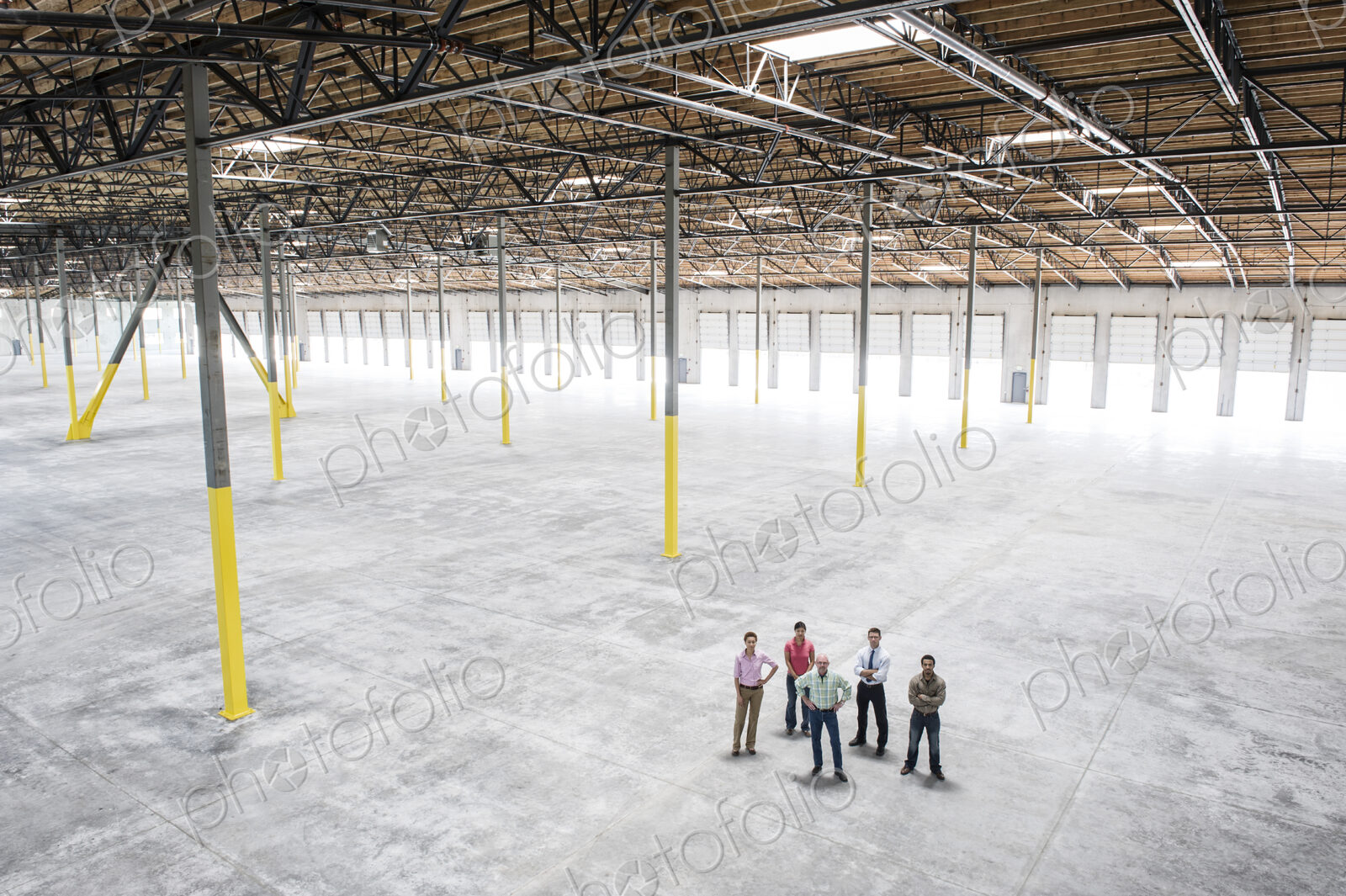 Multi-racial team of people going over plans for a new warehouse interior.