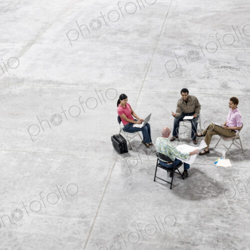 Multi-racial team of people going over plans for a new warehouse interior. Multi-racial team of people going over plans for a new warehouse interior.
