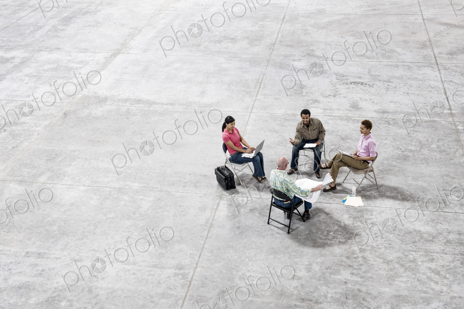 Multi-racial team of people going over plans for a new warehouse interior.