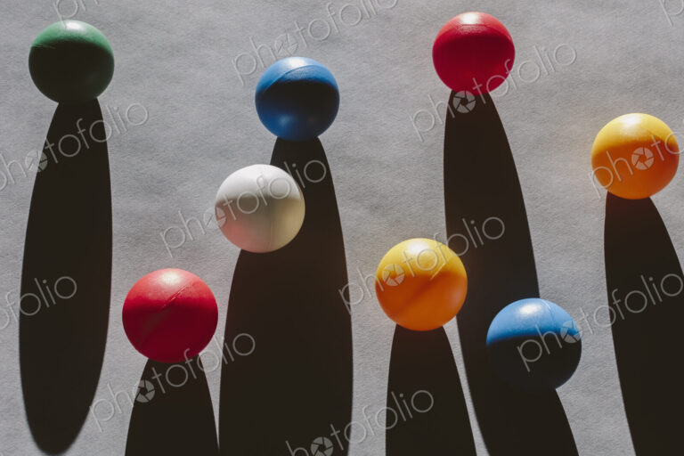 Multicolored balls arranged on wood background, casting long shadows