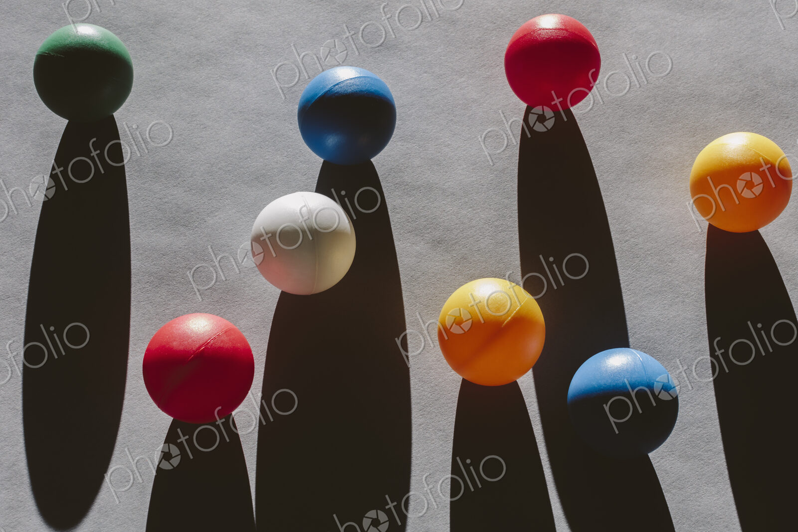 Multicolored balls arranged on wood background, casting long shadows