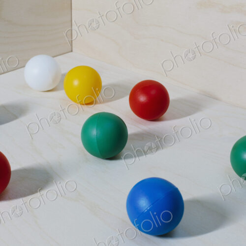 Multicoloured balls arranged on wood background, close up