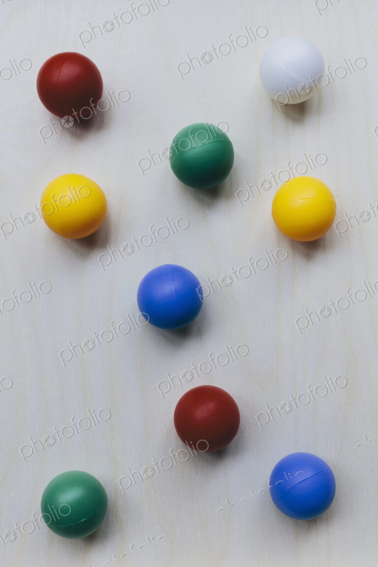 Multicoloured balls arranged on wood background, close up