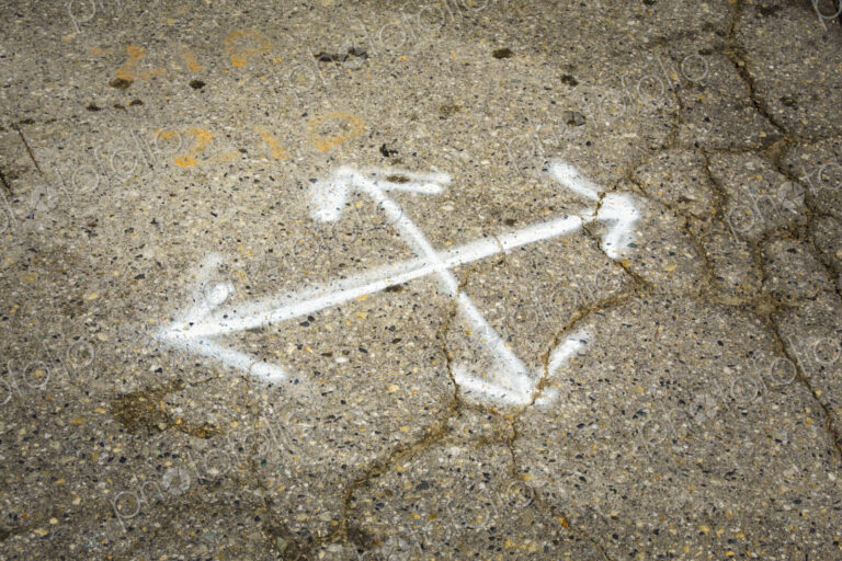 Multl-direction chalk arrows on pavement, cracks in the surface, potholes and concrete…