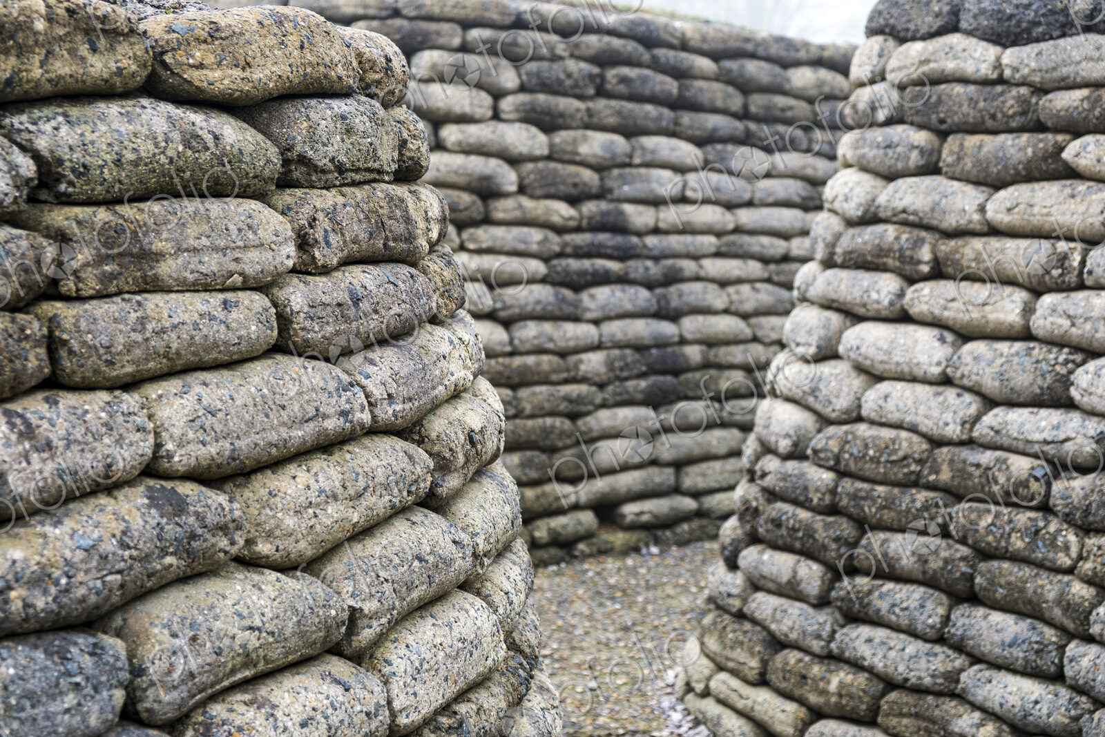 Narrow path in between curved walls of rounded concrete blocks.