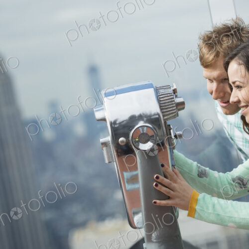 New York City. An observation deck overlooking the Empire State Building. A young…