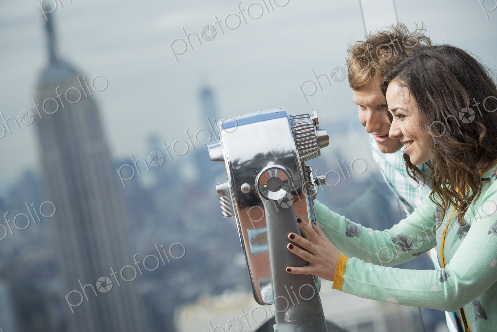 New York City. An observation deck overlooking the Empire State Building. A young…