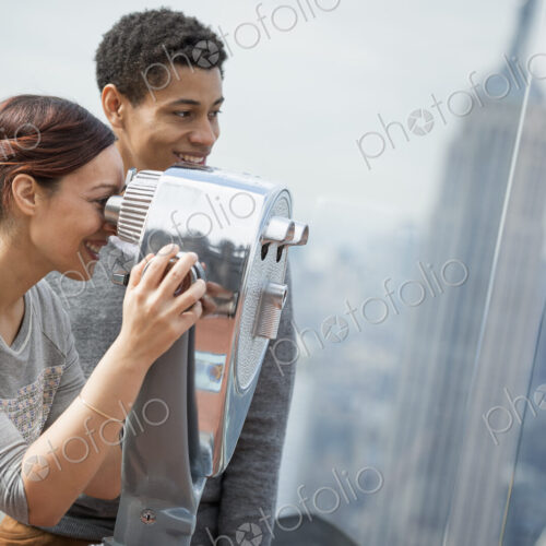 New York City. An observation deck overlooking the Empire State Building. A young…