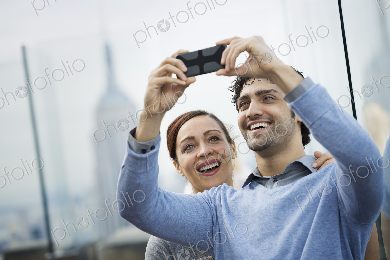 New York City. An observation deck overlooking the Empire State Building. A young…