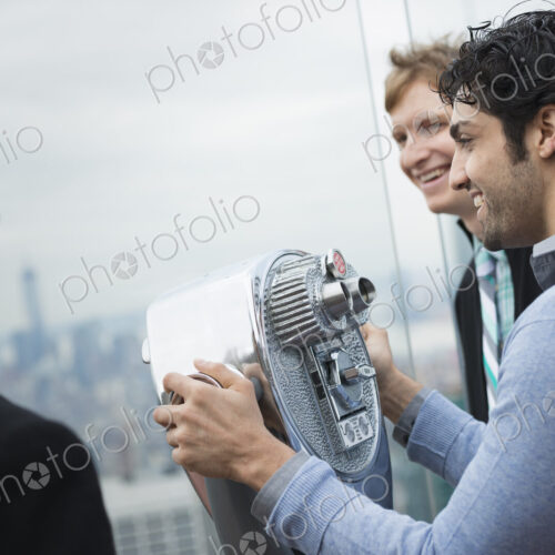 New York City. An observation deck overlooking the Empire State Building. Three young…