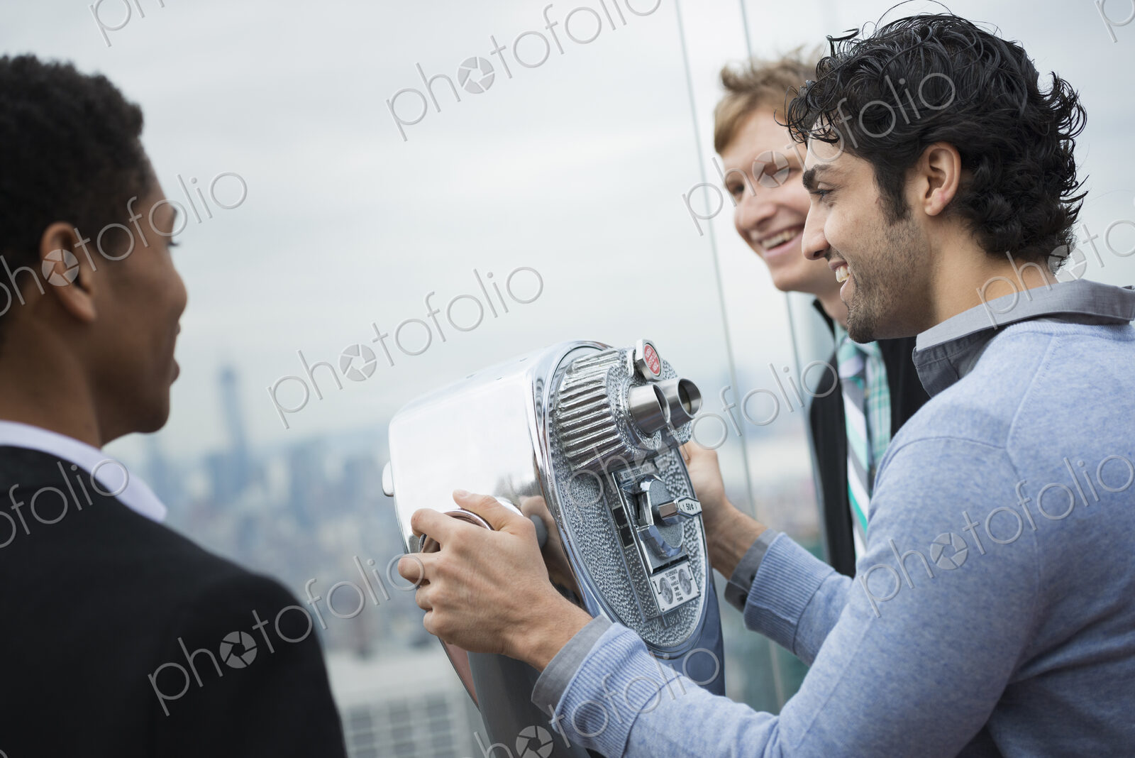 New York City. An observation deck overlooking the Empire State Building. Three young…