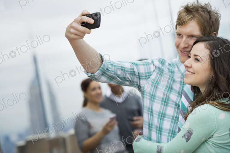 New York City. An observation deck overlooking the Empire State Building. Two couples…