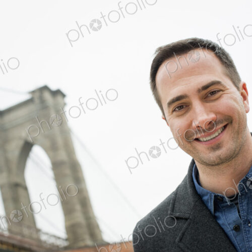 New York city, the Brooklyn Bridge crossing over the East River. A man looking at the… New York city, the Brooklyn Bridge crossing over the East River. A man looking at the…