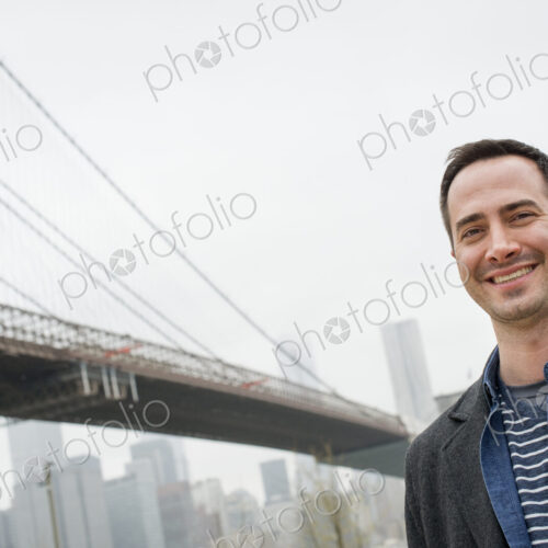 New York city, the Brooklyn Bridge crossing over the East River. A man wearing a grey… New York city, the Brooklyn Bridge crossing over the East River. A man wearing a grey…