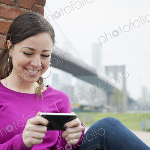 New York city, the Brooklyn Bridge crossing over the East River. A woman sitting…
