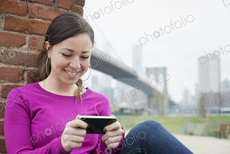 New York city, the Brooklyn Bridge crossing over the East River. A woman sitting…