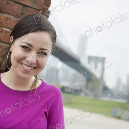 New York city, the Brooklyn Bridge crossing over the East River. A woman sitting…