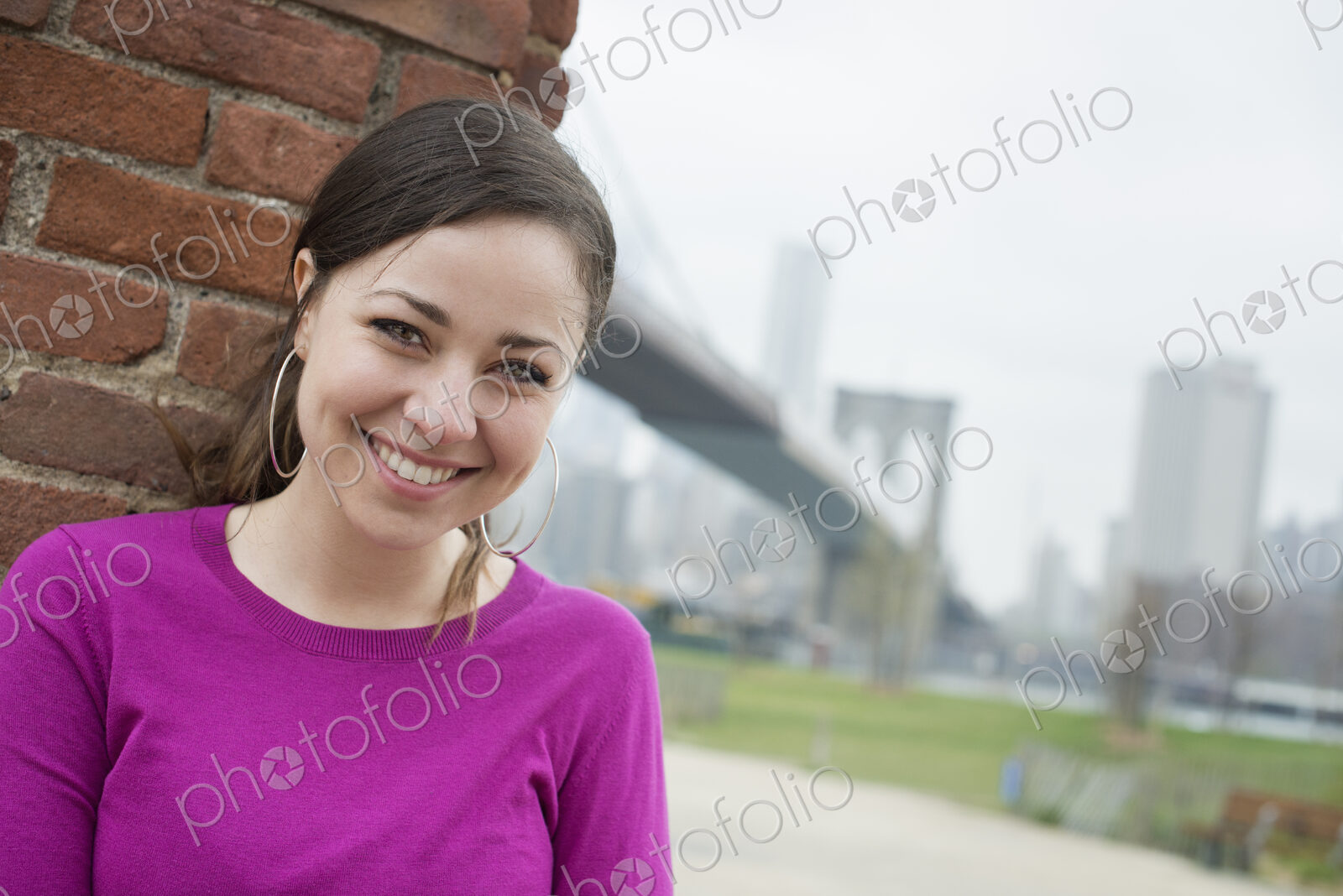 New York city, the Brooklyn Bridge crossing over the East River. A woman sitting…
