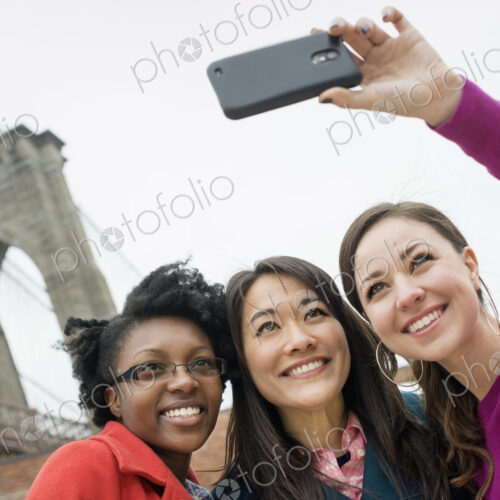 New York city, the Brooklyn Bridge crossing over the East River. Three women in a row,… New York city, the Brooklyn Bridge crossing over the East River. Three women in a row,…