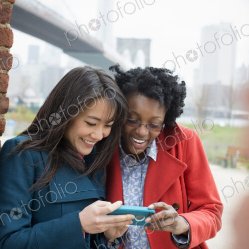New York city, the Brooklyn Bridge crossing over the East River. Two women, side by… New York city, the Brooklyn Bridge crossing over the East River. Two women, side by…