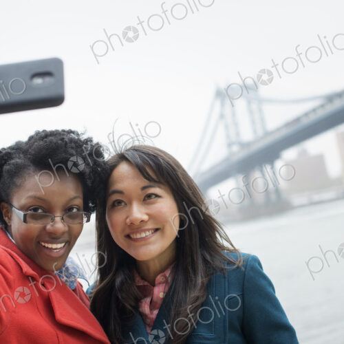 New York city. The Brooklyn Bridge crossing over the East River. A couple, two women,…