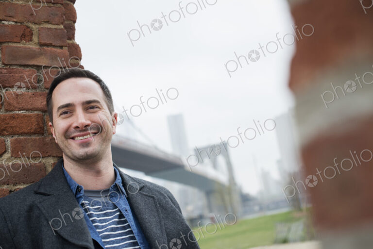 New York city. The Brooklyn Bridge crossing over the East River. A man leaning against…