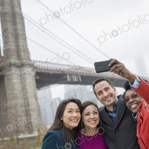 New York city. The Brooklyn Bridge crossing over the East River. Four friends taking a…