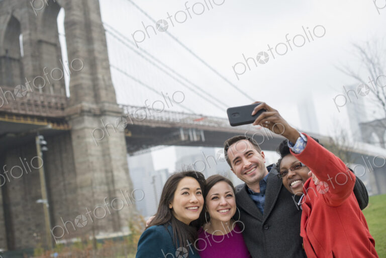 New York city. The Brooklyn Bridge crossing over the East River. Four friends taking a…