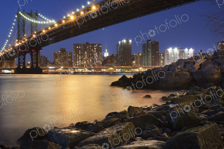 Night view towards Manhattan from Brooklyn, with the Manhattan Bridge spanning the…