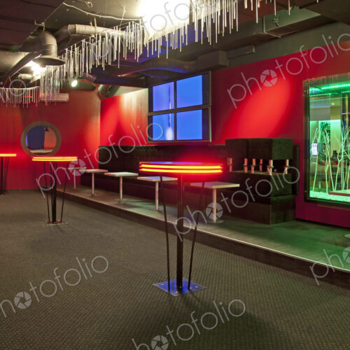 Nightclub interior, hospitality venue and colourful lighting, seatings and tables.