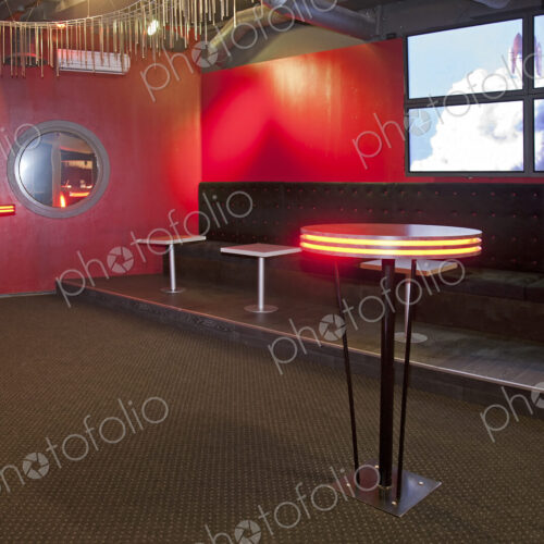 Nightclub interior, hospitality venue and colourful lighting, seatings and tables.
