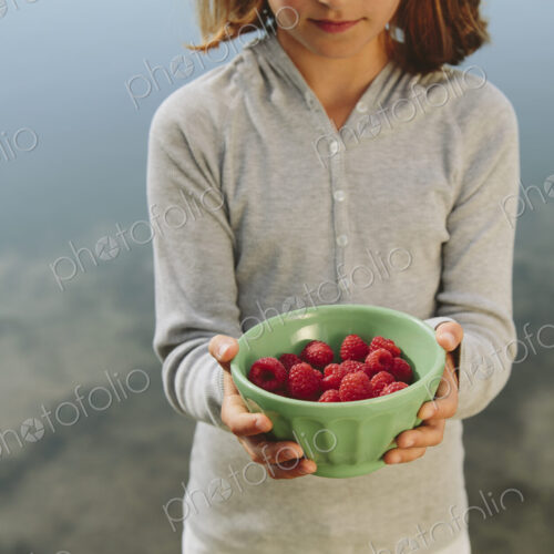 Nine year old girl holding bowl of organic raspberries Nine year old girl holding bowl of organic raspberries