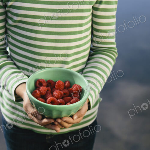 Nine year old girl holding bowl of organic raspberries Nine year old girl holding bowl of organic raspberries