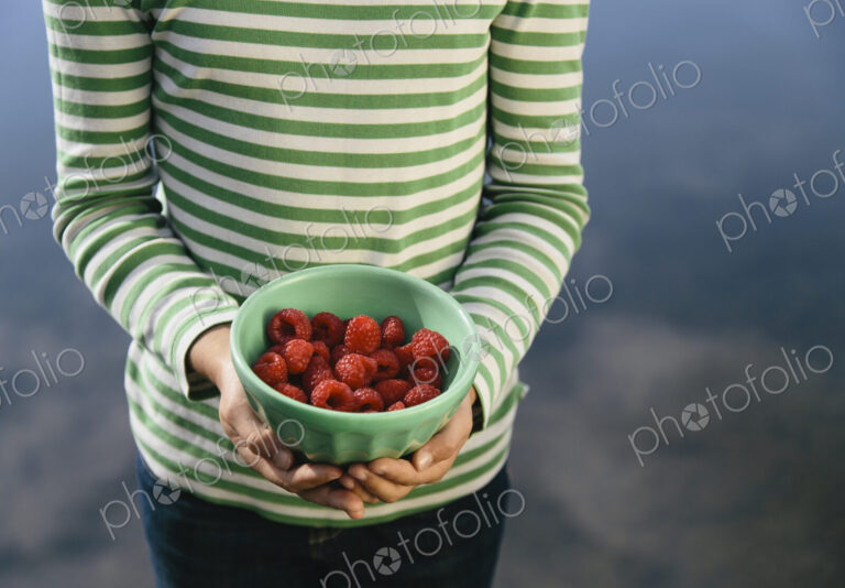 Nine year old girl holding bowl of organic raspberries